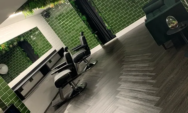 A barber chair against the green tiled wall at ATMOS